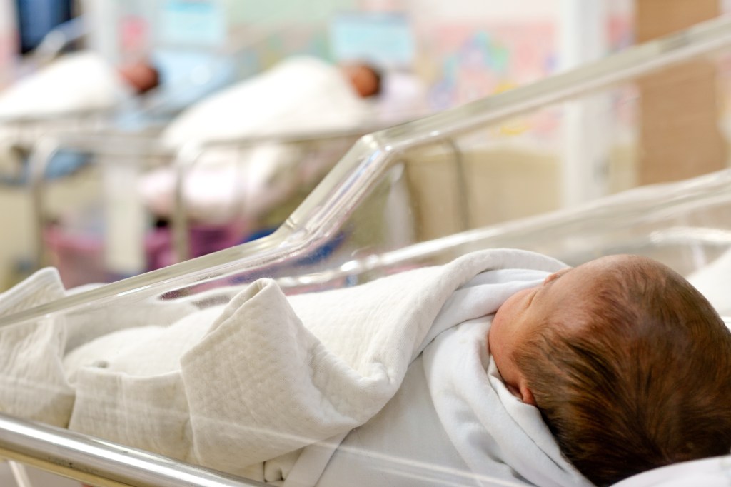 Newborn baby wrapped in a blanket in the nursery area of ​​a hospital